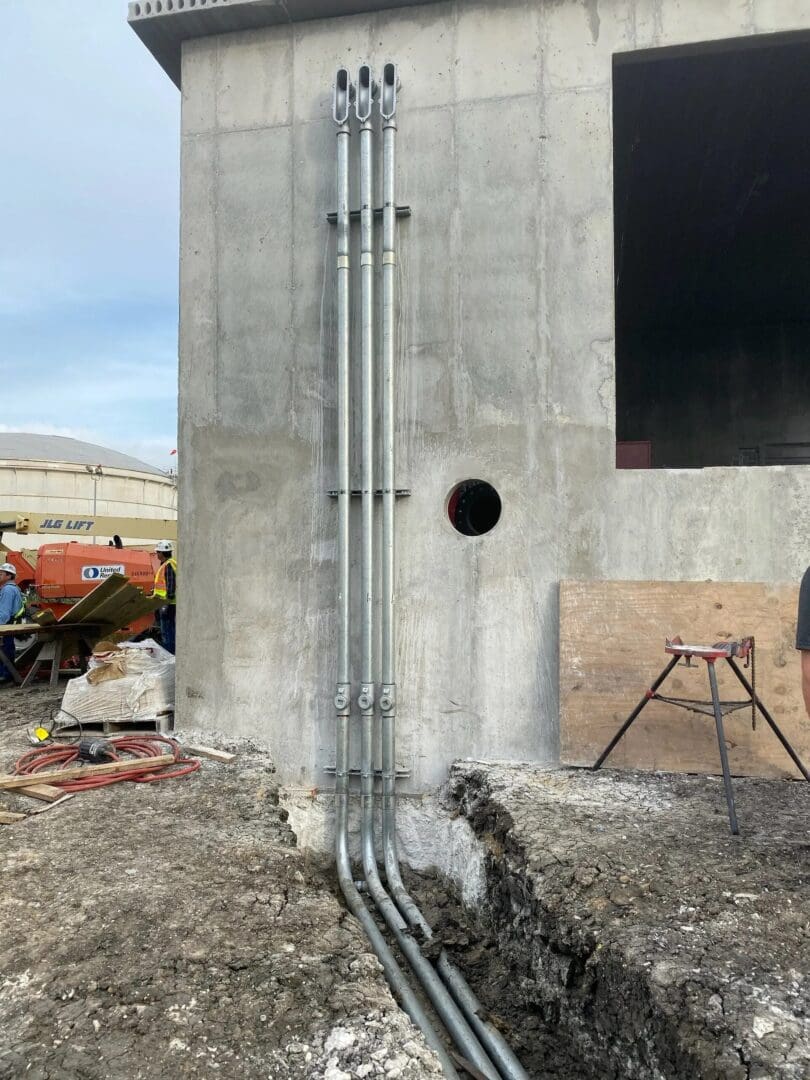 A cement pillar with pipes and wires on it.